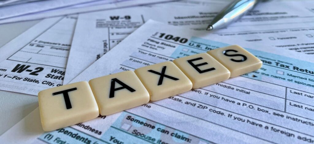Low angle of letter tiles with the word TAXES on a variety of tax forms.
