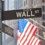 Wall street sign near stock market with american flags index annuity stock market index list