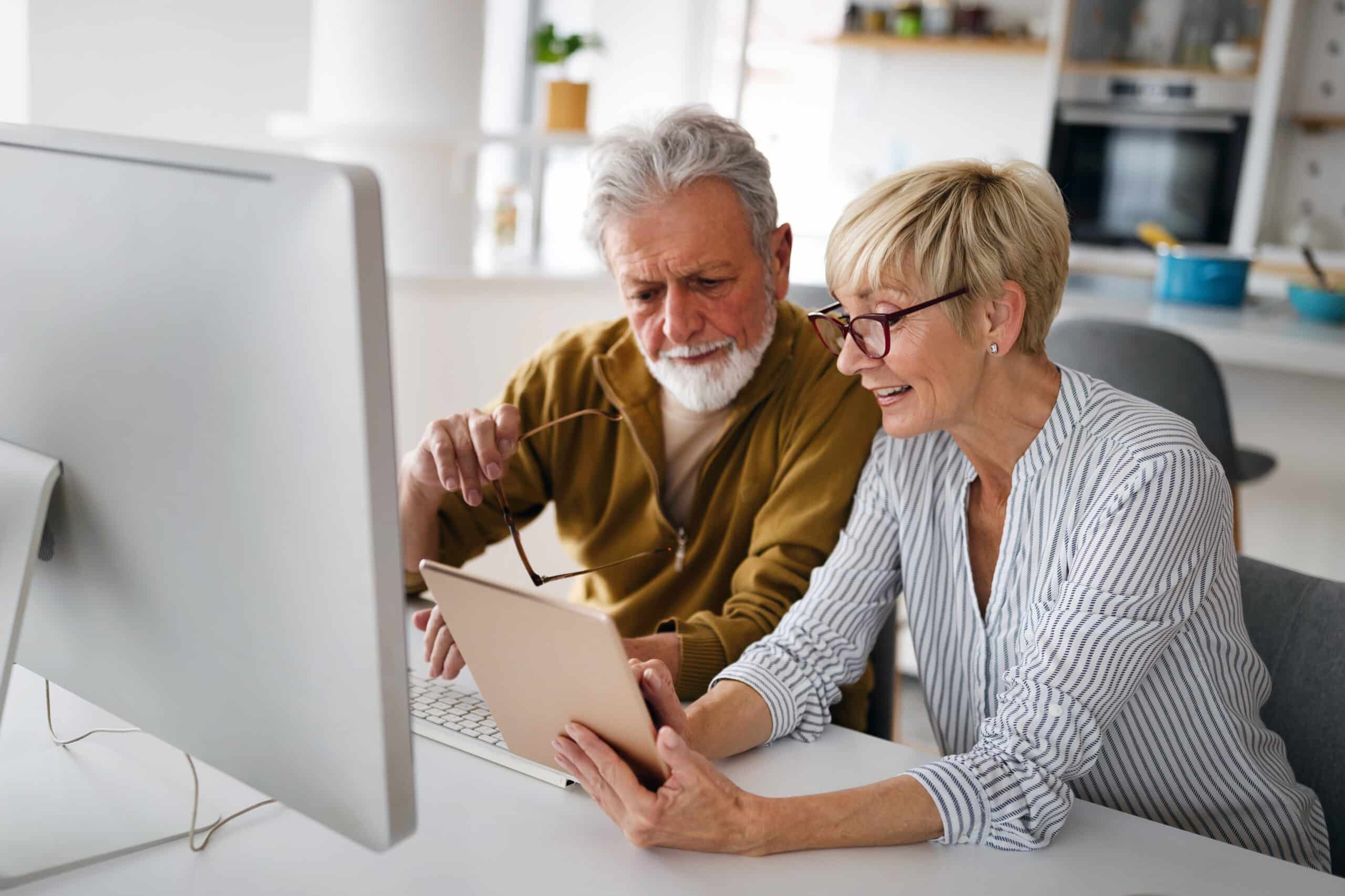 Immediate Annuity Payouts: Senior woman helping senior man to use computer